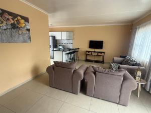 Una sala de estar con dos sofás y una cocina. en Casa Palm and Tide, en Swakopmund