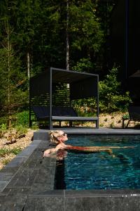 a woman in a swimming pool next to a bench at Hotel Fischerwirt Natur WaldSPA in Faistenau