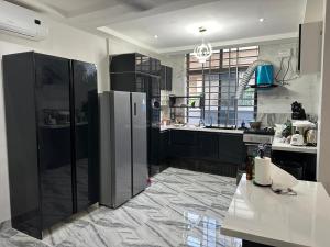 a kitchen with black cabinets and a refrigerator at Keloma Homes in Bolgatanga