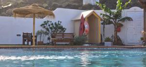a swimming pool with an umbrella and chairs and a bench at Finca de Sal in Villa de Mazo