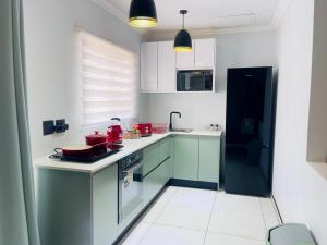 a kitchen with white cabinets and red appliances at ANG COMSAT Guesthouse in Northam