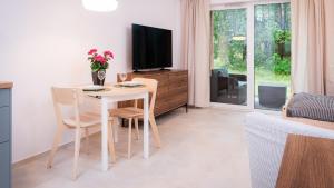 a living room with a table with chairs and a tv at Apartament A03 Karwica Zapach Lasu in Karwica