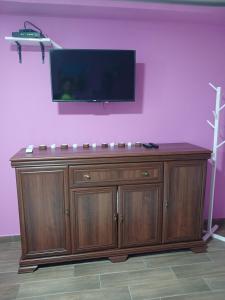 a large wooden cabinet with a flat screen tv on a pink wall at Apartman IN Pančevo in Pančevo