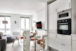 une cuisine avec des armoires blanches et un salon dans l'établissement Appartement Quartier Tour Eiffel Free Netflix, à Paris 8 autres photos