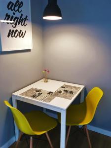 biurko z 2 żółtymi krzesłami i stół z napisem w obiekcie Apartament blisko Centrum w Warszawie