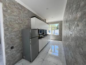 a kitchen with a stainless steel refrigerator and white cabinets at AllGreen House in Gabala