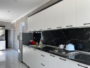a kitchen with white cabinets and a black counter top at AllGreen House in Gabala +11 photos