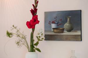 a vase with red flowers in it next to a painting at Stilvolles Ambiente im grünen Hamburg! in Hamburg +19 photos