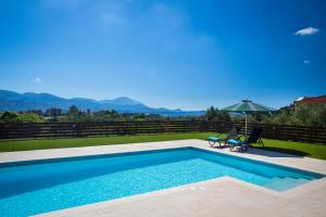 a swimming pool with a table and an umbrella at Armonia Villas in Lixouri