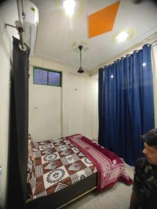 Un dormitorio con una cama y una cortina azul. en Shyama Guest House, en Vrindāvan