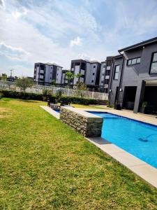a swimming pool in a yard in front of some buildings at Urban Contempo Lush in Fourways