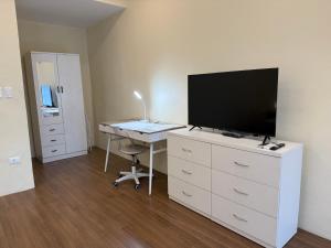 a room with a desk with a television and a desk with a computer at Lucia’s Place in Tanauan