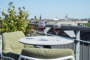 two glasses of wine sitting on a table on a balcony at Hotel Nora Copenhagen in Copenhagen