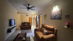 a living room with a couch and a ceiling fan at Easy Homestay in Tampin