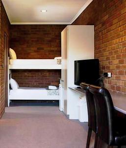 a room with a desk with a computer and a television at Fountain Court Motor Inn Albury in Albury