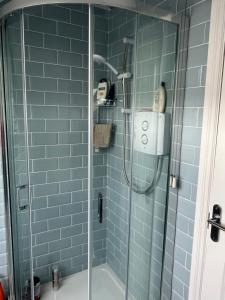a bathroom with a shower with blue tiles at Glencross Cottage in Rathmullan +24 photos