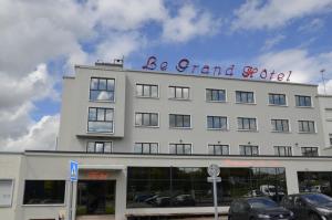 a large white building with a sign on top of it at Le Grand Hotel in Maubeuge