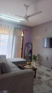 een woonkamer met een bank en een plafondventilator bij Flynn Stays in Bamburi