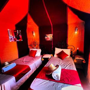 two beds in a room with red lighting at ibis merzouga camp in Merdani