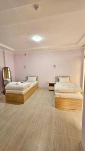 Habitación con 2 camas, paredes de color rosa y suelo de madera. en Sokin Palace, en Bukhara