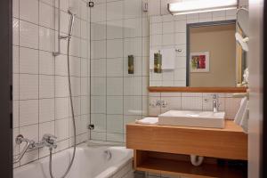 a bathroom with a tub and a sink and a shower at Hotel Gasthof Krönele in Lustenau +140 photos