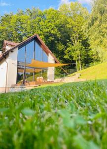 a house with large glass windows and a green field at Joli Chalet in Râşnov