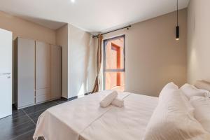 Un dormitorio con una cama blanca con una ventana. en Galleria Roma Aparthotel, en Tirana
