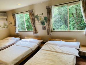 two beds in a room with two windows at 菜音天然温泉別荘 in Tsu