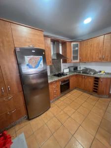 Una cocina con gabinetes de madera y un refrigerador de acero inoxidable. en Casa mis Nietas, en San José