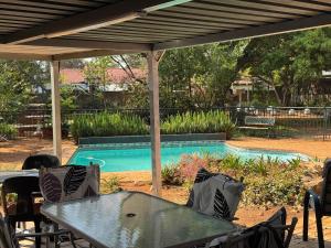 a table and chairs under a pergola next to a swimming pool at Jolly Suites in Midrand