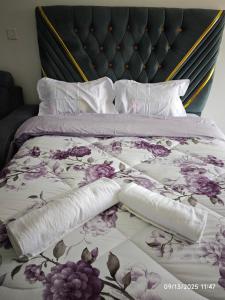a bed with a purple floral bedspread and pillows at Tsavo Stanley in Kiambu
