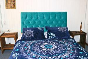 a bed with a green headboard and blue pillows at Hostal Punto Rockstar in Osorno
