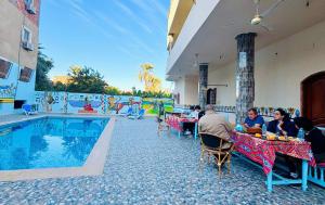 a group of people sitting at tables next to a pool at Luxor Hotel in Luxor