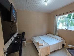 a bedroom with a bed and a flat screen tv at Recanto da natureza em Anchieta in Anchieta