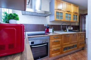 kuchnia z drewnianymi szafkami i czerwoną lodówką w obiekcie Piso Museo del Realismo-Catedral-Alcazaba-Free Parking-Wifi-Aire acondicionado w mieście Almería