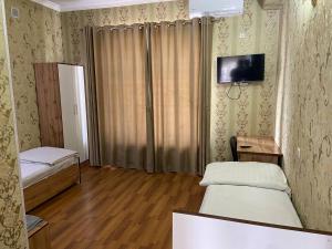 a room with two beds and a tv on the wall at Ziyo hotel in Yalanghoch +5 photos