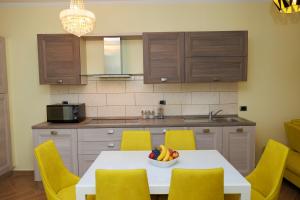 a kitchen with a table with yellow chairs and a bowl of fruit at Elena Seaview Apartment in Vlorë