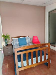 a bedroom with a wooden bed with a red chair at Hostal Genoveva in San Salvador