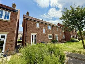 a row of brick buildings in a yard at Baileys Beach House - Part of the The Bay Filey Holiday Village with pool, gym and direct beach access, pub, restaurant, tennis and meadows walks in Filey