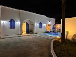a white house with a swimming pool at night at Dar Inès in Al Maqārisah