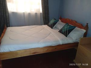 a bed with white sheets and pillows in a room at Polycap Cottage Home in Murangʼa