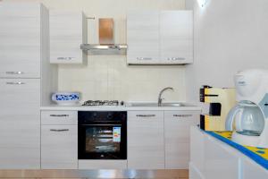 a kitchen with white cabinets and a sink and an oven at Villa Marianna - Almiddina in Telti