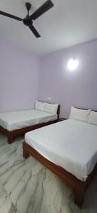 two beds in a room with a ceiling fan at BANGALOUR ELITE Residency Attibele in Bangalore