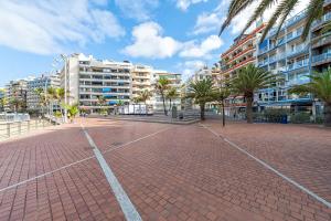 a brick parking lot with palm trees and buildings at Lunin Apartments in Las Palmas de Gran Canaria