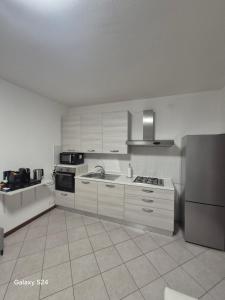 a kitchen with white cabinets and a stove and refrigerator at Confortevole alloggio in Piacenza