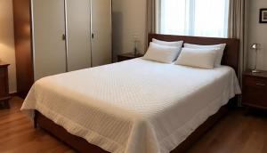 カラチにあるHotel Rest Innの大きな白いベッドと枕が2つある寝室