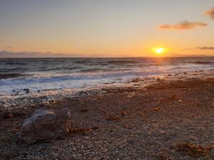 a rock on the beach with the sunset in the background at Ample town house in Workington, West Lakes, Lake District in Workington