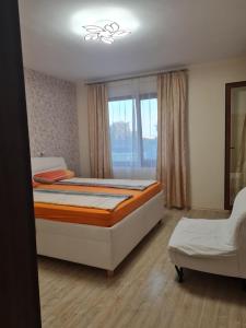 a bedroom with a bed and a chair and a window at Botanika in Varna City +5 photos