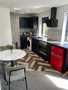 a kitchen with black cabinets and a white table and a table at Affordable Serviced Apartment close to City Centre in Peterborough