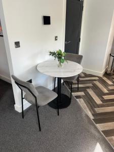 a white table with two chairs and a vase of flowers at Affordable Serviced Apartment close to City Centre in Peterborough